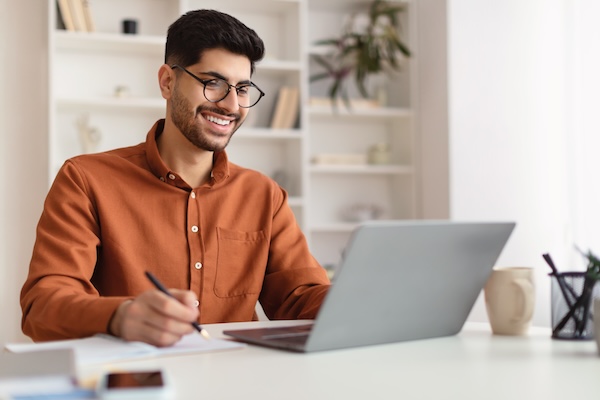 Portrait,Of,Young,Smiling,Arab,Man,In,Glasses,Using,Laptop